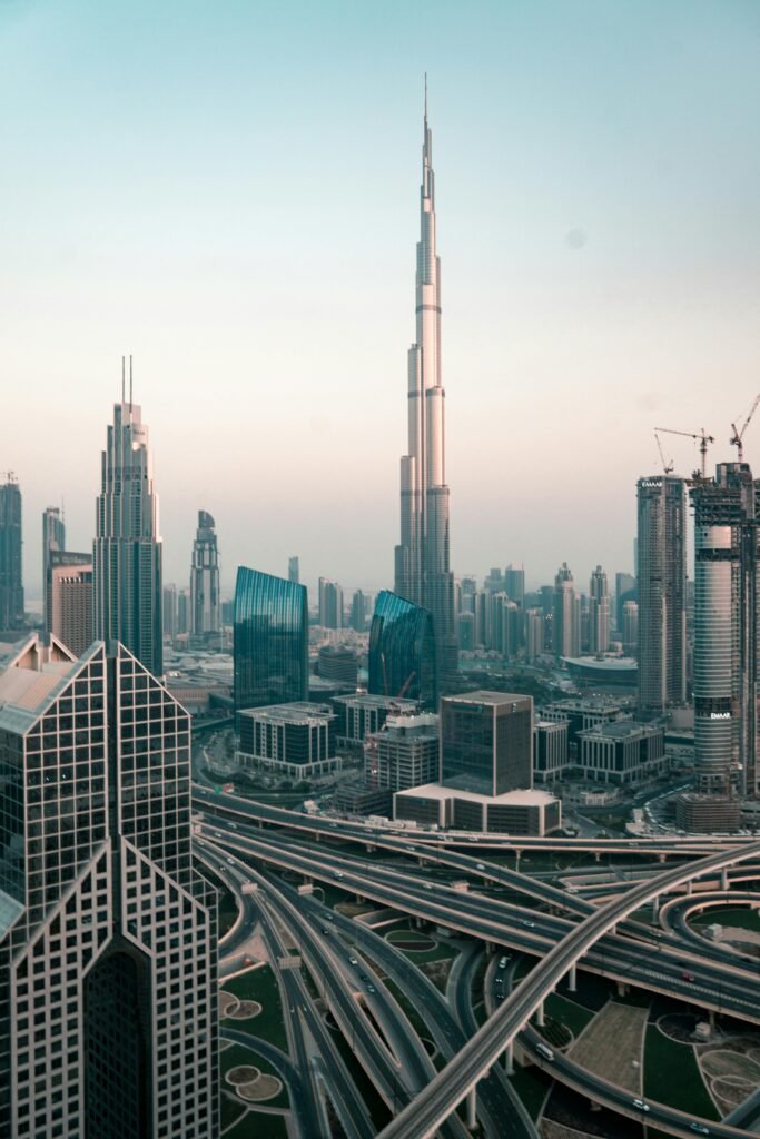 Aerial view of Dubai's skyline with Burj Khalifa and intricate highway system at sunset.